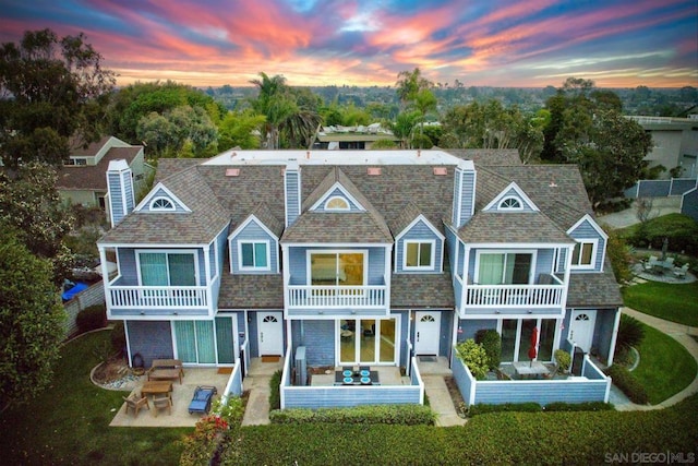 back house at dusk with a balcony and a patio area