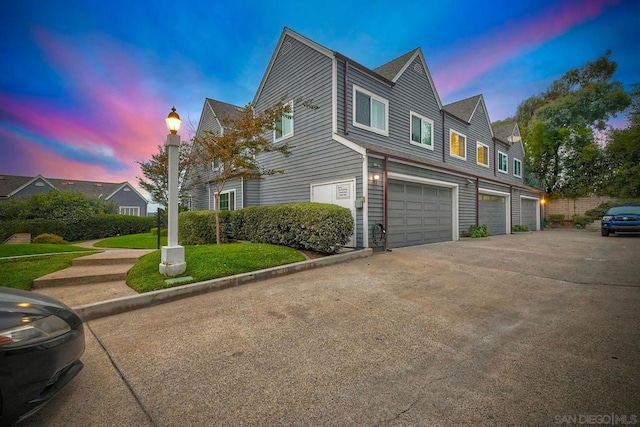 property exterior at dusk with a garage and a lawn