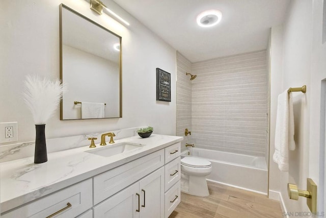 full bathroom with tiled shower / bath combo, vanity, hardwood / wood-style floors, and toilet