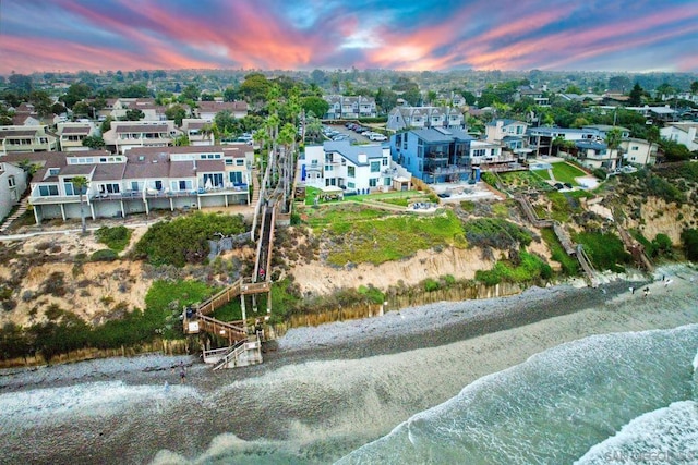 aerial view at dusk with a view of the beach and a water view