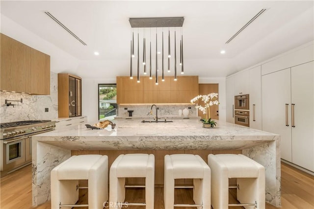 kitchen featuring double oven range, tasteful backsplash, a breakfast bar, and sink