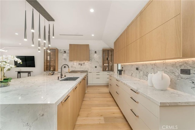 kitchen with decorative light fixtures, backsplash, sink, and light brown cabinets