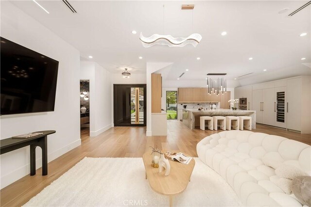 living room with a chandelier and light wood-type flooring