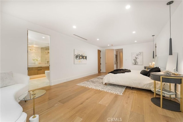 bedroom with connected bathroom and light hardwood / wood-style floors