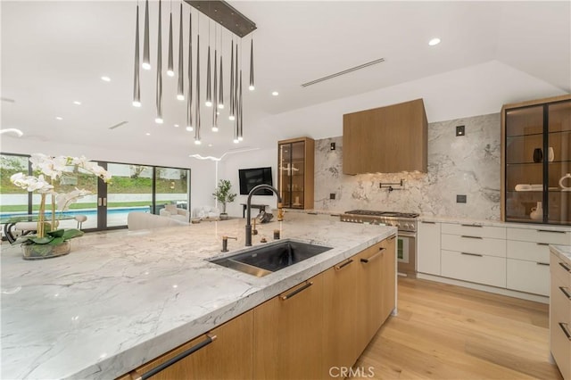 kitchen featuring white cabinetry, backsplash, light stone countertops, pendant lighting, and sink