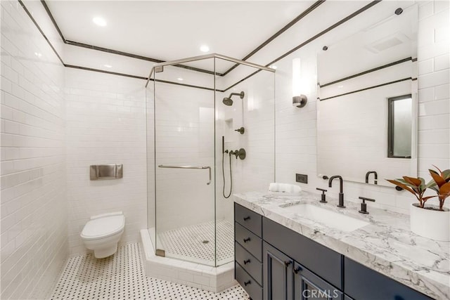 bathroom with tile walls, walk in shower, vanity, and toilet