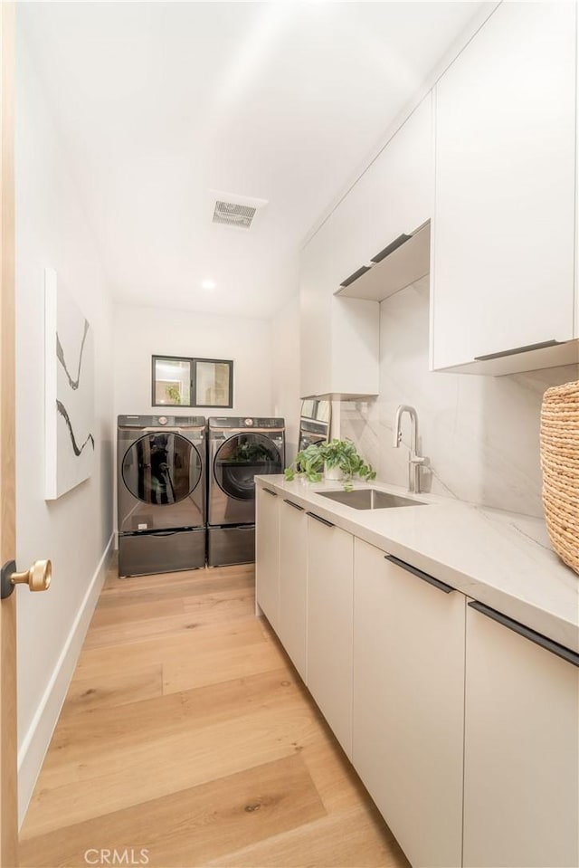 washroom with cabinets, separate washer and dryer, sink, and light wood-type flooring