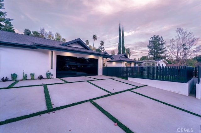 patio terrace at dusk featuring a garage