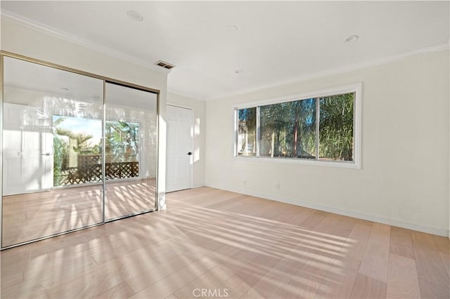 spare room with ornamental molding and light hardwood / wood-style floors