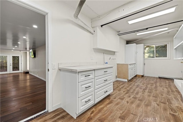 kitchen featuring light hardwood / wood-style floors, white cabinets, lofted ceiling with beams, and french doors