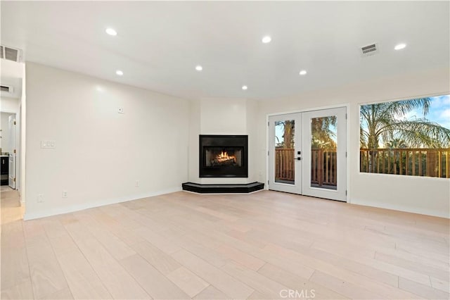 unfurnished living room featuring french doors and light hardwood / wood-style flooring