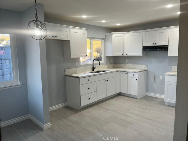 kitchen featuring white cabinetry, sink, and decorative light fixtures