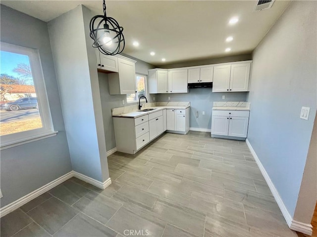 kitchen featuring white cabinets, pendant lighting, a healthy amount of sunlight, and sink