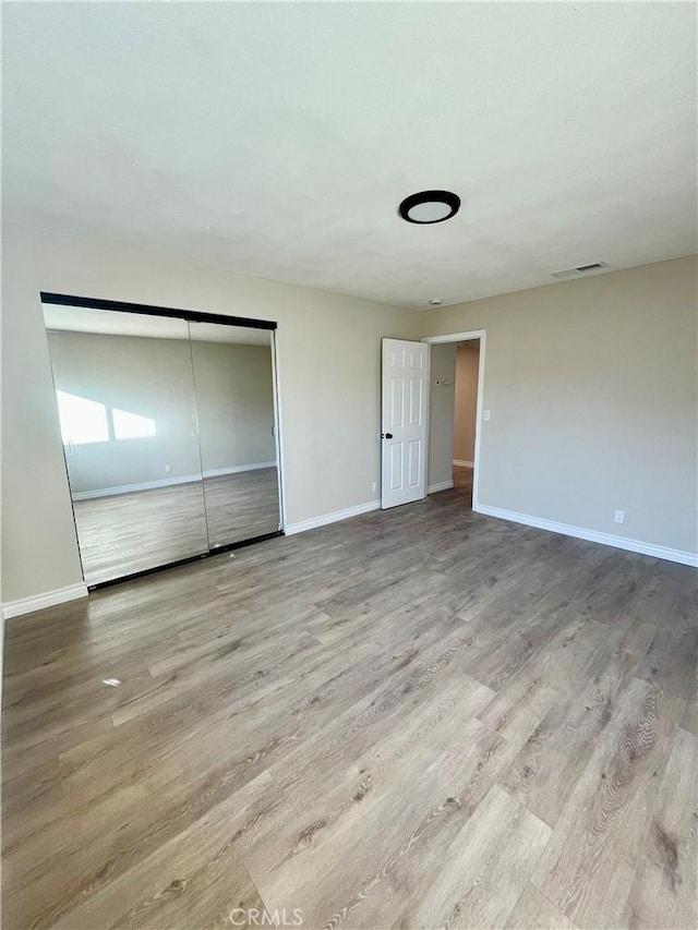 unfurnished bedroom with a closet and light hardwood / wood-style flooring