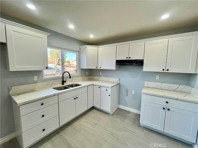 kitchen featuring white cabinets, light stone countertops, and sink