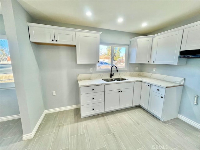 kitchen featuring light stone countertops, sink, and white cabinets