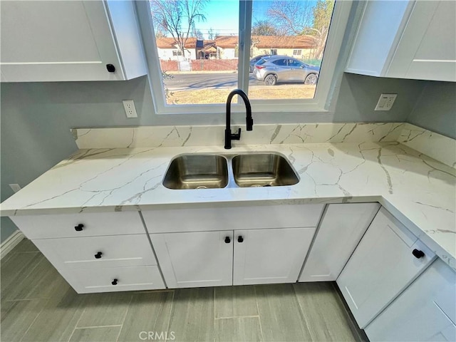 kitchen featuring white cabinetry, sink, and light stone counters