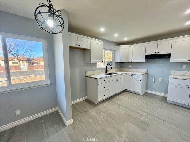 kitchen featuring white cabinets, pendant lighting, and sink