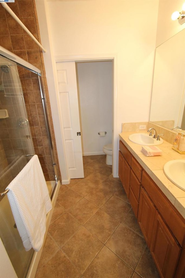 bathroom featuring toilet, vanity, tile patterned floors, and a shower with shower door