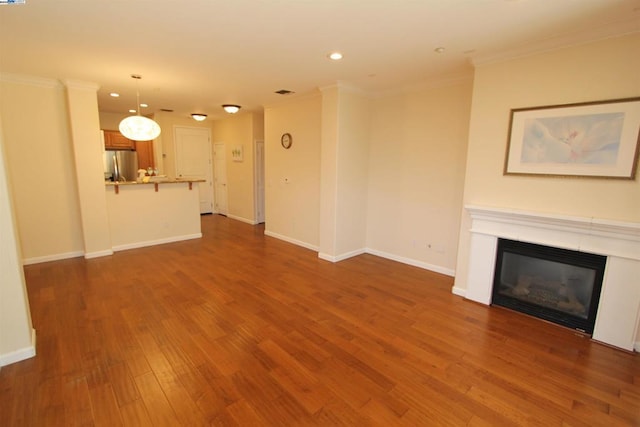 unfurnished living room featuring dark wood-type flooring and crown molding