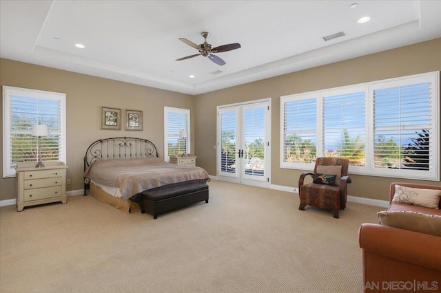 bedroom featuring ceiling fan, light colored carpet, a tray ceiling, and access to outside