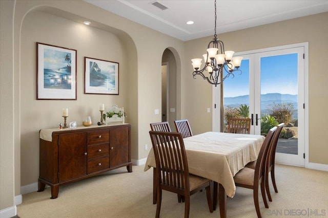 carpeted dining space with french doors, a notable chandelier, and a mountain view