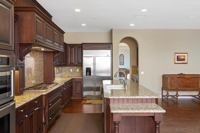 kitchen with decorative backsplash, sink, appliances with stainless steel finishes, a kitchen breakfast bar, and dark brown cabinets