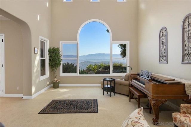 sitting room with light carpet, a towering ceiling, and a mountain view