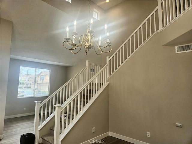 stairs featuring hardwood / wood-style flooring and a chandelier