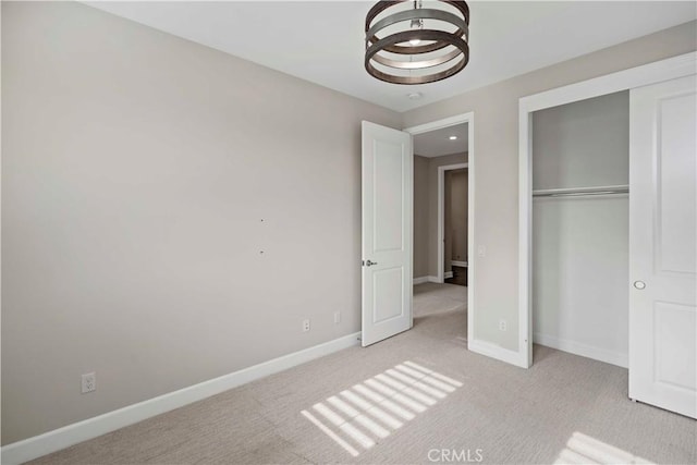 unfurnished bedroom with a closet, light colored carpet, and an inviting chandelier