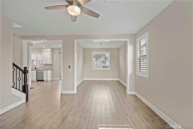 spare room with sink, ceiling fan with notable chandelier, and light hardwood / wood-style flooring