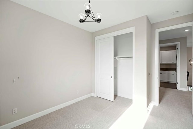 unfurnished bedroom featuring light carpet, a closet, and a notable chandelier