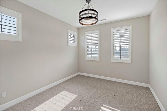 spare room with light colored carpet and a notable chandelier