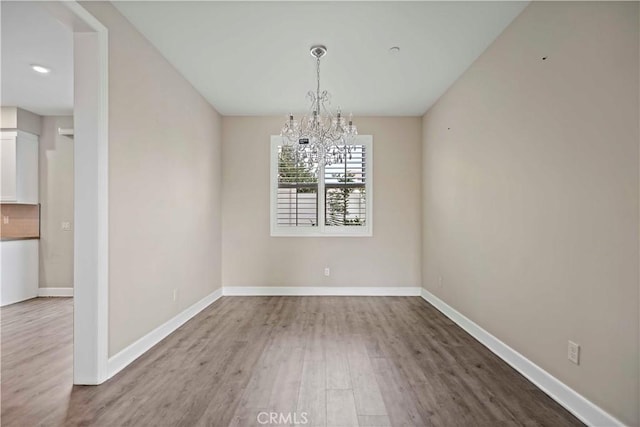 unfurnished dining area with a chandelier and hardwood / wood-style floors