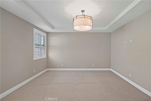 carpeted empty room with a tray ceiling