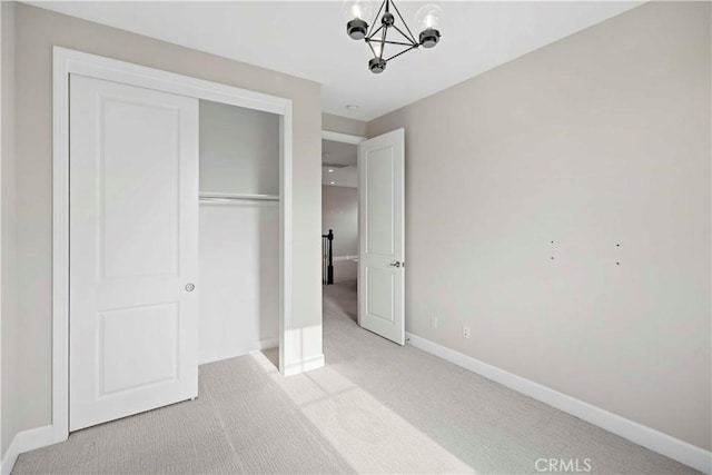 unfurnished bedroom featuring light carpet, a closet, and a chandelier