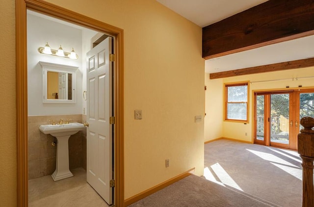 interior space featuring french doors, light colored carpet, sink, and tile walls