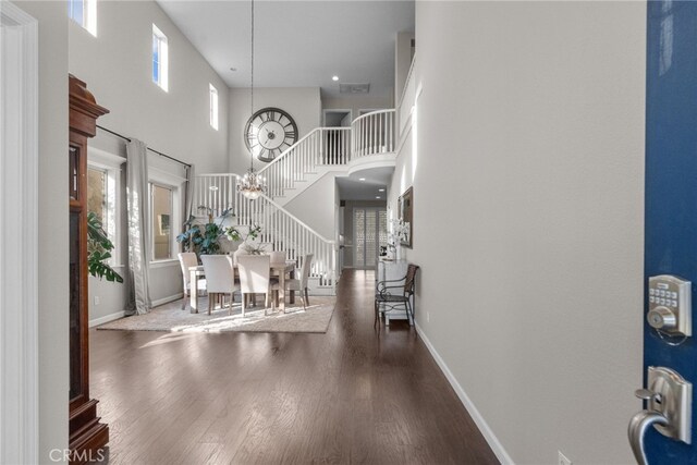 entrance foyer featuring a high ceiling, dark hardwood / wood-style flooring, plenty of natural light, and a notable chandelier