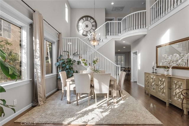 dining space with baseboards, wood finished floors, a high ceiling, stairs, and a chandelier