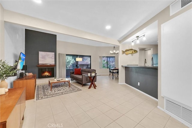 tiled living room featuring track lighting, sink, and a notable chandelier