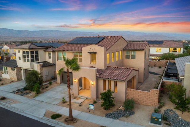 mediterranean / spanish home with a garage, solar panels, and a mountain view