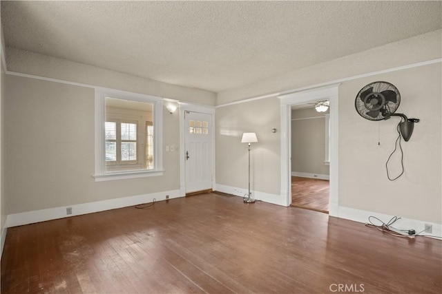 unfurnished living room with ceiling fan, baseboards, a textured ceiling, and wood finished floors