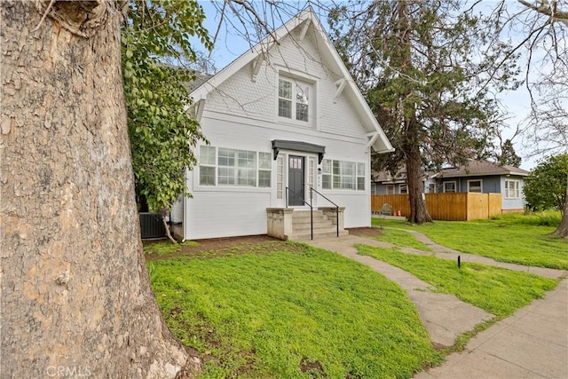 view of front facade with central AC, a front lawn, and fence