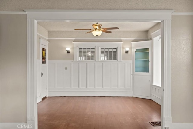 spare room with ceiling fan, a textured ceiling, wood finished floors, and ornamental molding