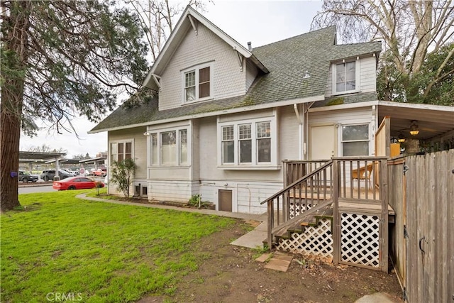 rear view of house with a yard and roof with shingles