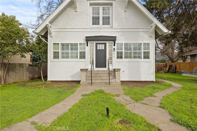 bungalow-style house with a front yard and fence