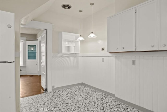 kitchen featuring white cabinets, decorative light fixtures, visible vents, and freestanding refrigerator