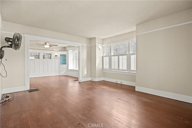 unfurnished living room with a textured ceiling, hardwood / wood-style flooring, baseboards, and ceiling fan