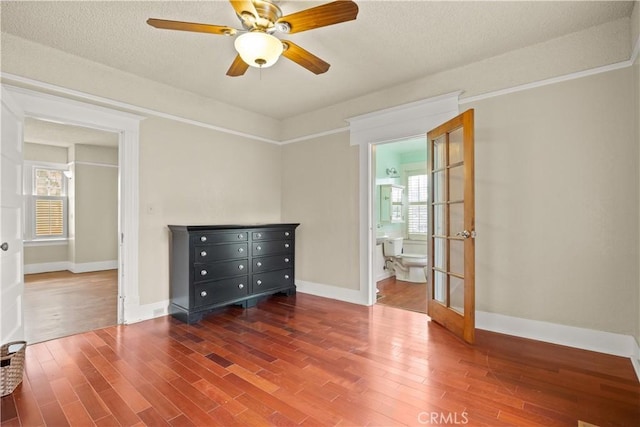 empty room with baseboards, a textured ceiling, ceiling fan, and wood finished floors