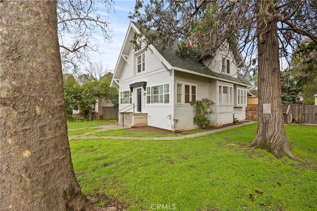 view of home's exterior featuring fence, a lawn, and roof with shingles